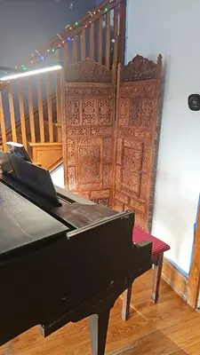 a black piano in a room with a wooden door at Old Charm Getaway in New Cumberland