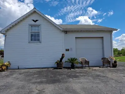 a white house with a garage with two chairs at Old Charm Getaway in New Cumberland