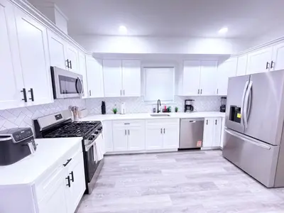 a white kitchen with white appliances and white cabinets at Luxury Stay in Newark