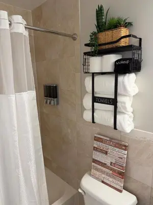 a bathroom with a toilet and towels on a shelf at Chic & Comfy Apartment
