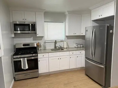 a kitchen with white cabinets and a stainless steel refrigerator at Chic & Comfy Apartment