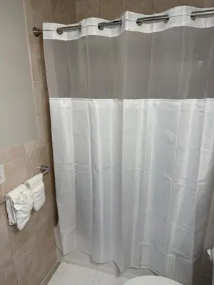 a bathroom with a shower with a white shower curtain at Chic & Comfy Apartment