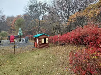 a wooden out house with a bench and a table at Charming Family Friendly House, Hot tub, Playroom in Long Pond