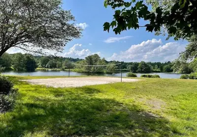 a volleyball court in a field next to a lake at Charming Family Friendly House, Hot tub, Playroom in Long Pond