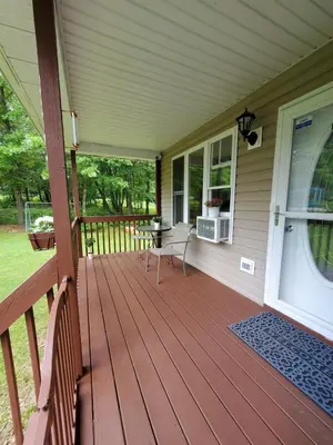 a wooden porch with a table and chairs on it at GreatEscape Nature Playground HiSpeedInternet in Long Pond