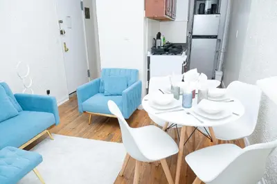 a dining room with a white table and blue chairs at Stylish2 Upper West Side Apartment 5-Min Walk to Central Park in New York