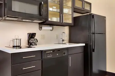 a kitchen with black cabinets and a black refrigerator at Candlewood Suites Vestal - Binghamton by IHG in Vestal
