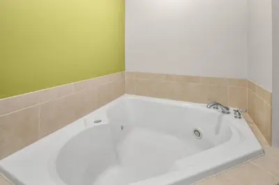 a white tub in a bathroom with a green wall at Holiday Inn Express & Suites Wilmington-Newark by IHG in Newark