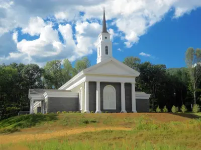 a white church with a steeple on top of a hill at Holiday Inn Express & Suites Gibson by IHG in New Milford