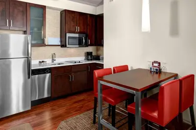 a kitchen with a table with red chairs and a refrigerator at Residence Inn by Marriott Philadelphia Airport in Philadelphia