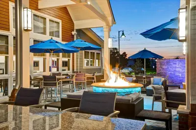 a patio with a fire pit with chairs and blue umbrellas at Residence Inn by Marriott Hamilton in Hamilton