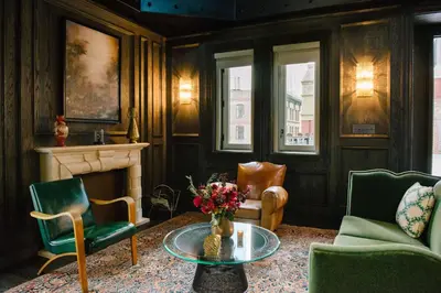 a living room with chairs and a table and a fireplace at The Beekman, A Thompson Hotel, by Hyatt in New York