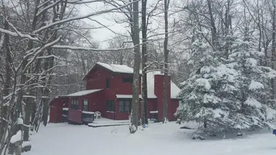 a red cabin in the snow with a christmas tree at Chalet renovated Near Casino, Camelback , Kalahari 4bdrms firepit hot tub game room in Tobyhanna