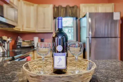 a bottle of wine in a basket with two wine glasses at Chalet renovated Near Casino, Camelback , Kalahari 4bdrms firepit hot tub game room in Tobyhanna