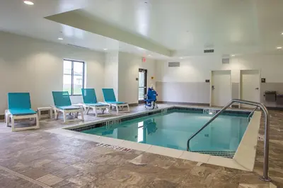a swimming pool with blue chairs and a person in a room at Comfort Inn PA Turnpike - I-81 in Carlisle