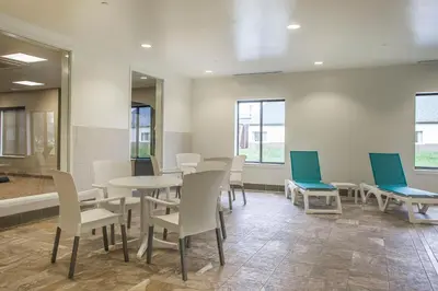 a waiting room with tables and chairs and windows at Comfort Inn PA Turnpike - I-81 in Carlisle