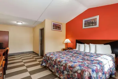 a hotel room with a bed and a red wall at Travelodge by Wyndham Jersey City in Jersey City
