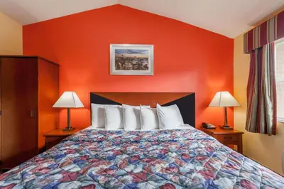 a bedroom with a bed with an orange wall at Travelodge by Wyndham Jersey City in Jersey City