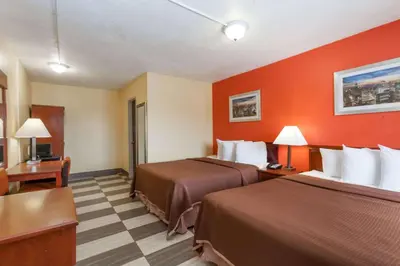 a hotel room with two beds and orange walls at Travelodge by Wyndham Jersey City in Jersey City