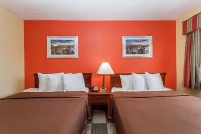 two beds in a hotel room with orange walls at Travelodge by Wyndham Jersey City in Jersey City
