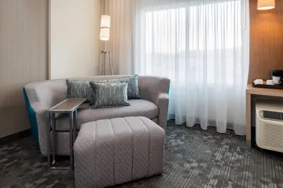a room with a chair and a table and a window at Courtyard by Marriott Elmira Horseheads in Horseheads