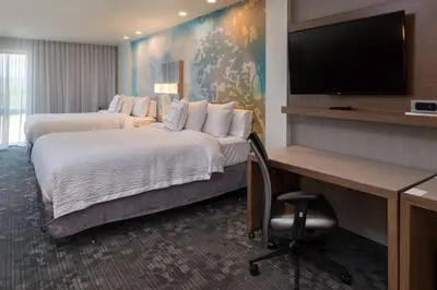 a hotel room with two beds and a desk and a flat screen tv at Courtyard by Marriott Elmira Horseheads in Horseheads