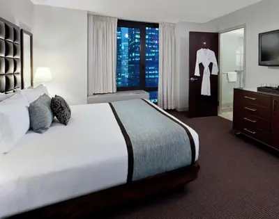 a hotel room with a bed with a dresser and a television at Distrikt Hotel New York City, Tapestry Collection by Hilton in New York