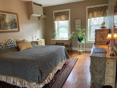 a bedroom with a bed and a table and windows at Hollinger House in Lancaster