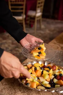 a person holding a plate of fruit on a table at Hollinger House in Lancaster