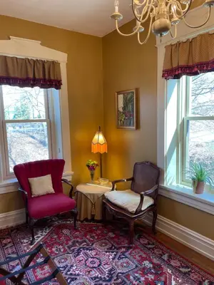 a living room with two chairs and a table and windows at Hollinger House in Lancaster