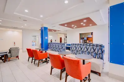 a waiting room with orange chairs and tables at Holiday Inn Express Hotel & Suites Chester by IHG in Chester