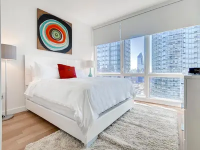 a white bedroom with a large bed and windows at Global Luxury Suites at Sky in New York