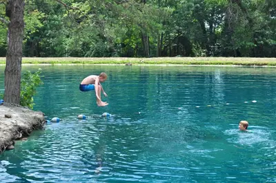 a man jumping into a lake with other people in the water at Spring Gulch Screened Park Model 7 in Mount Airy