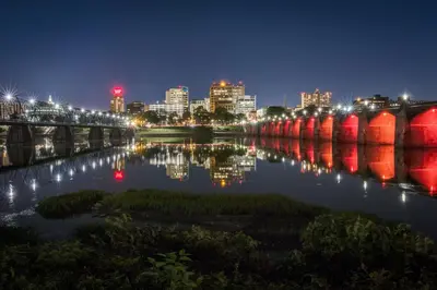 a city skyline with a bridge and a river at night at Holiday Inn Express Harrisburg East by IHG in Harrisburg