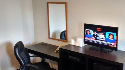 a room with a desk with a television and a mirror at Gene's Motel in Cinnaminson