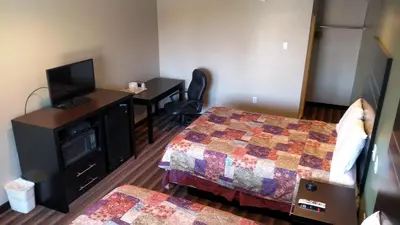 a room with two beds and a desk with a television at Gene's Motel in Cinnaminson