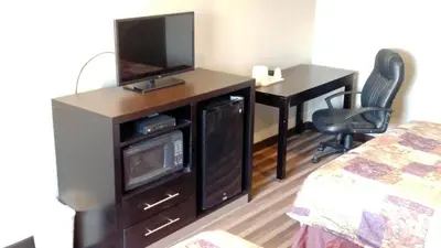 a room with a television and a desk with a bed at Gene's Motel in Cinnaminson