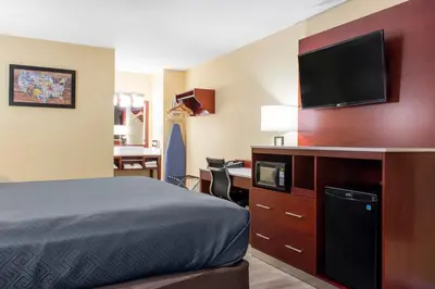a hotel room with a bed and a flat screen tv at Escape Inn Hershey in Hershey