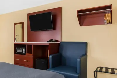 a room with a bed and a chair and a television at Escape Inn Hershey in Hershey
