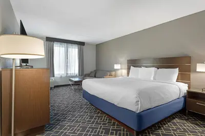 a hotel room with a large bed and a couch at Best Western Hunt's Landing Hotel Matamoras Milford in Matamoras