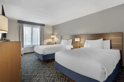a hotel room with two beds and a television at Best Western Hunt's Landing Hotel Matamoras Milford in Matamoras