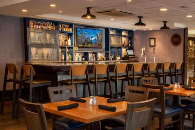 a bar in a restaurant with wooden tables and chairs at Four Points Philadelphia City Center in Philadelphia