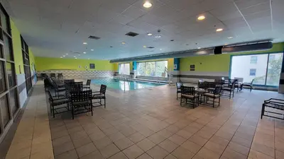 a pool room with tables and chairs and a swimming pool at Crowne Plaza Hotel Harrisburg-Hershey by IHG in Harrisburg