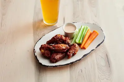 a plate of chicken wings and vegetables with a glass of orange juice at Holiday Inn Lansdale-Hatfield by IHG in Kulpsville