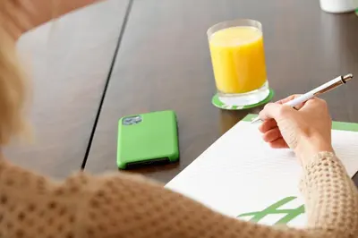a woman writing on a paper with a glass of orange juice at Holiday Inn Lansdale-Hatfield by IHG in Kulpsville