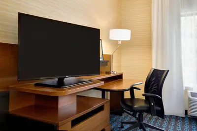 a room with a desk with a large screen television at Fairfield Inn & Suites by Marriott Lancaster East at The Outlets in Lancaster
