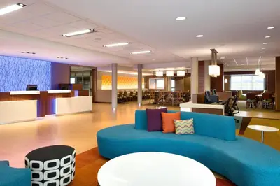 an office lobby with a blue couch and tables at Fairfield Inn & Suites by Marriott Lancaster East at The Outlets in Lancaster