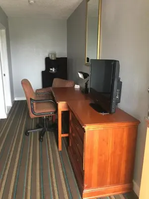 a room with a desk with a television and a chair at Scottish Inn and Suites - Bensalem-Philadelphia in Bensalem