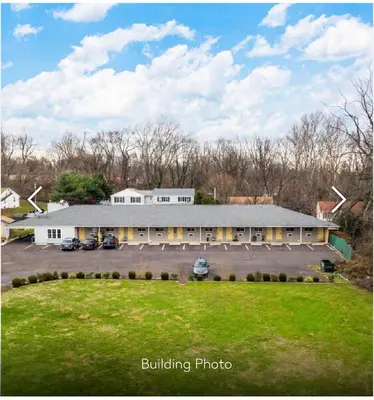 a large white building with a large parking lot at Scottish Inn and Suites - Bensalem-Philadelphia in Bensalem