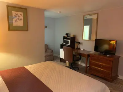 a bedroom with a bed and a desk with a television at Scottish Inn and Suites - Bensalem-Philadelphia in Bensalem